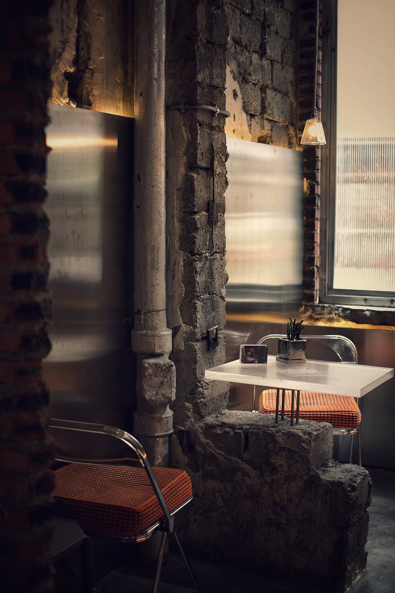 Orange chair and white table between raw stone pillars